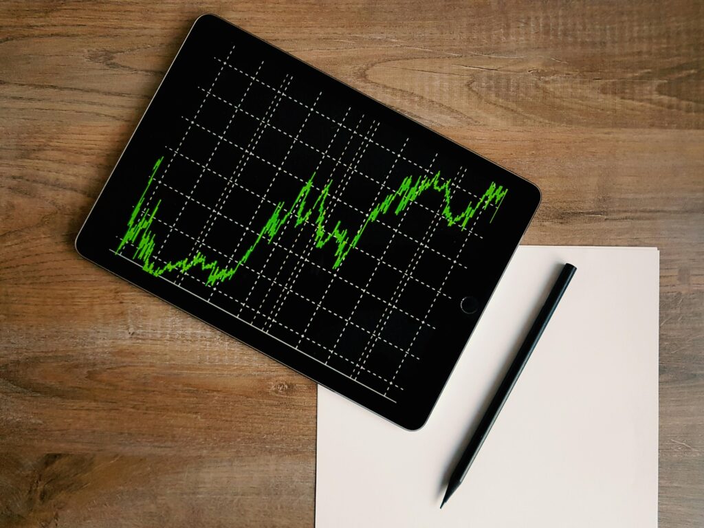 uptrend chart in a tablet screen on table with pen and paper